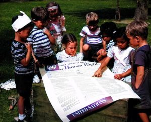 Fotografia tirada de crianças da Escola Infantil Internacional das Nações Unidas a olhar para um cartaz da Declaração Universal dos Direitos Humanos. Datada do século XX. (Foto por: Universal History Archive / UIG via Getty Images)